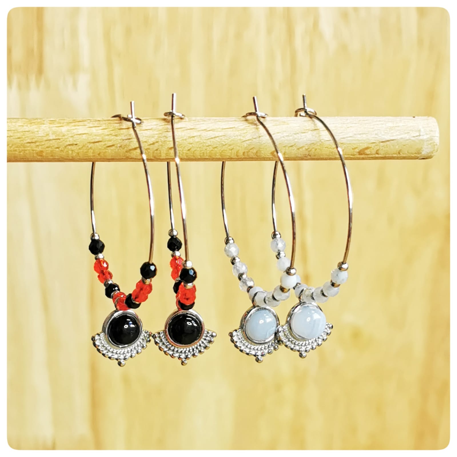 Joséphine bleu vs rouge/noir - créoles côte à côte sur présentoir en bois, comparaison des coloris.